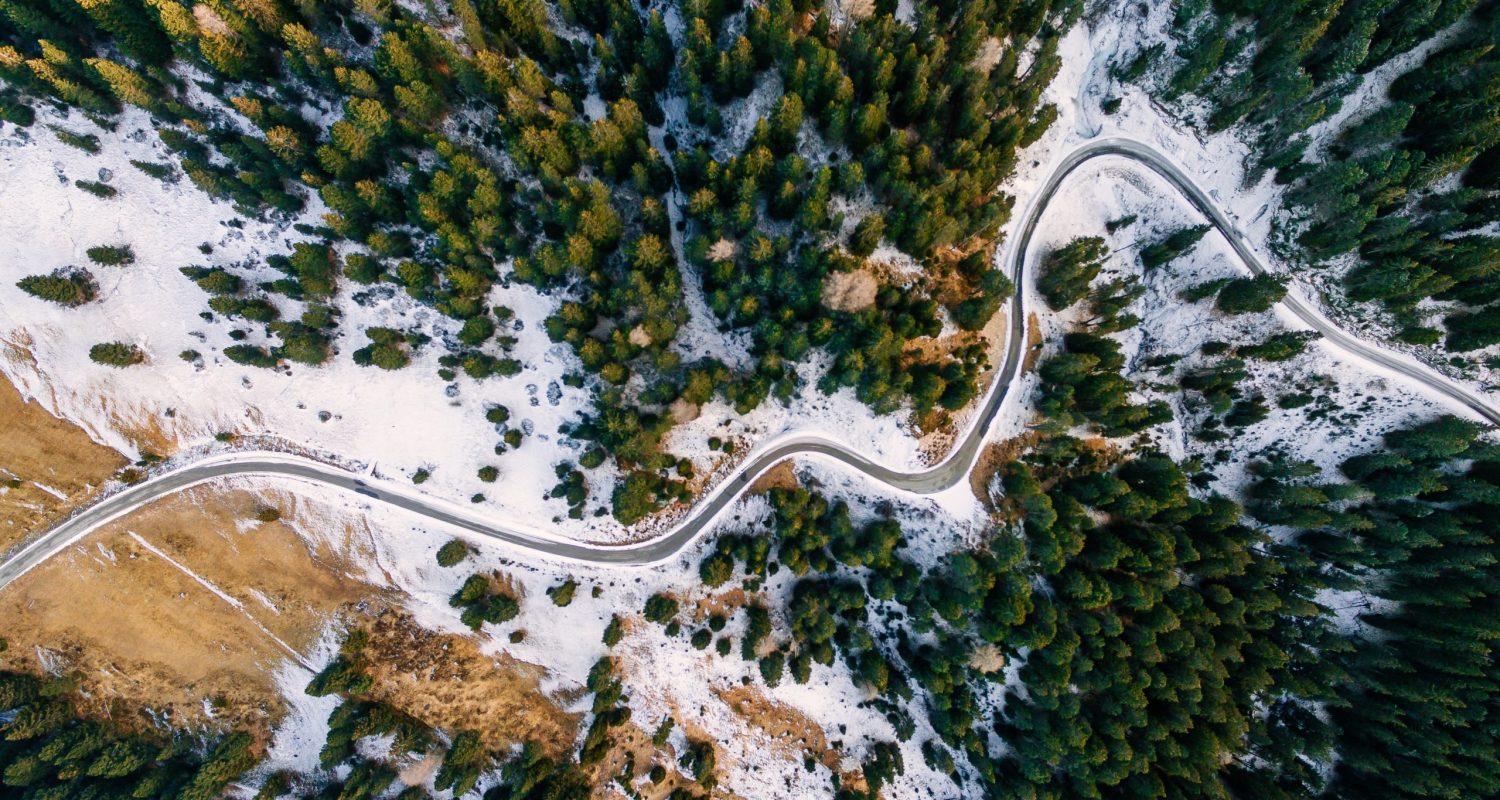Aerial view of snowy forest with a road. Captured from above with a drone. Dolomites - Italy